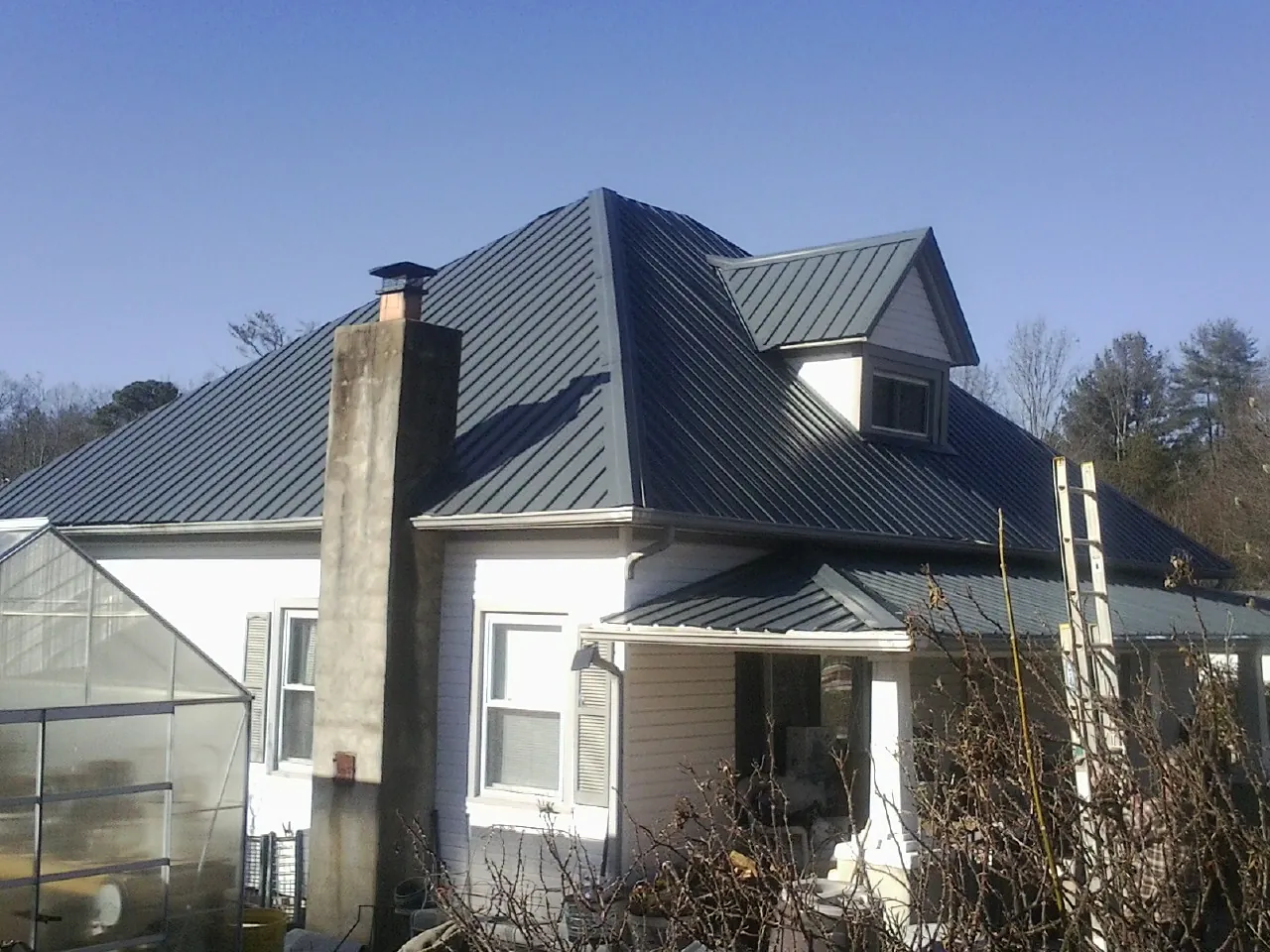 Dark blue standing seam metal roof on a white farmhouse with dormer — Slate & Tile Roof Repair by Roofing Brothers in Antwerp