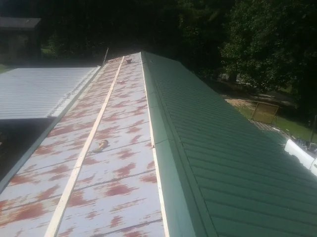 Old rusted panels beside newly installed green metal roofing — Wind Damage Roof Repair by Roofing Brothers in Antwerp