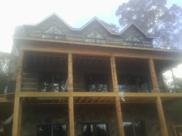 Dormers and porch framing on a large log home under construction — Roof Coating work by our crew in Antwerp