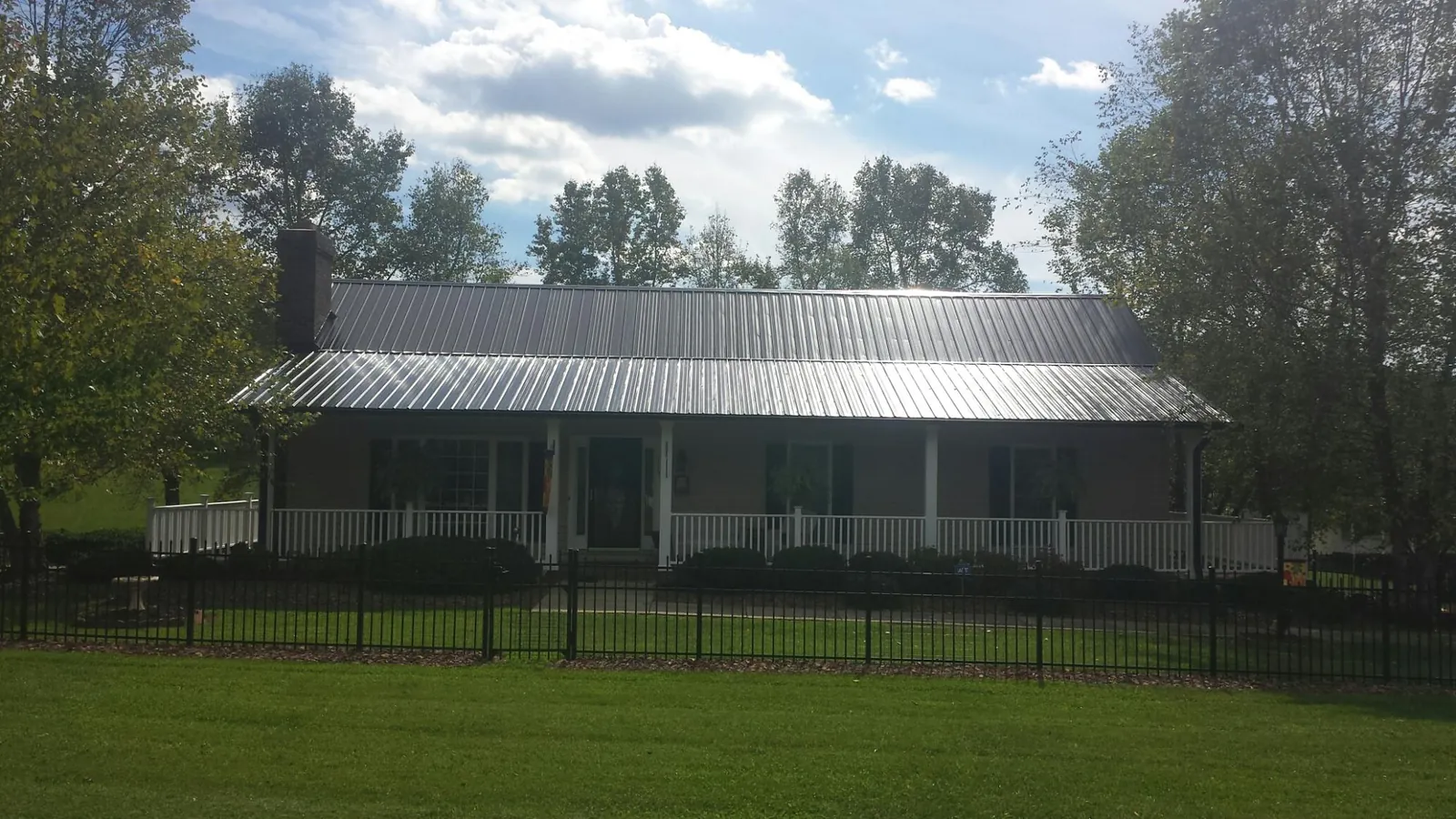 Gray metal roof on a brick ranch with a full width front porch — Gutter Guard Installation work by our crew in Antwerp