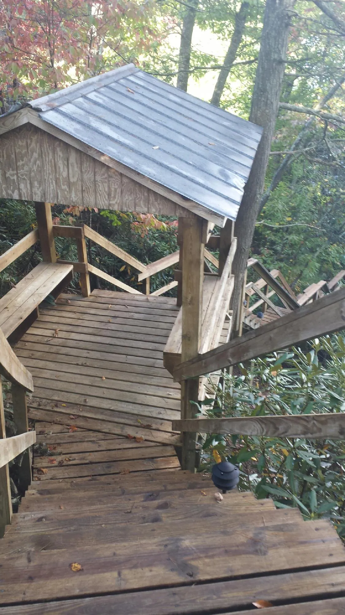 Metal roofed shelter over wooden steps on a wooded walkway — Skylight Repair & Installation work by our crew in Antwerp