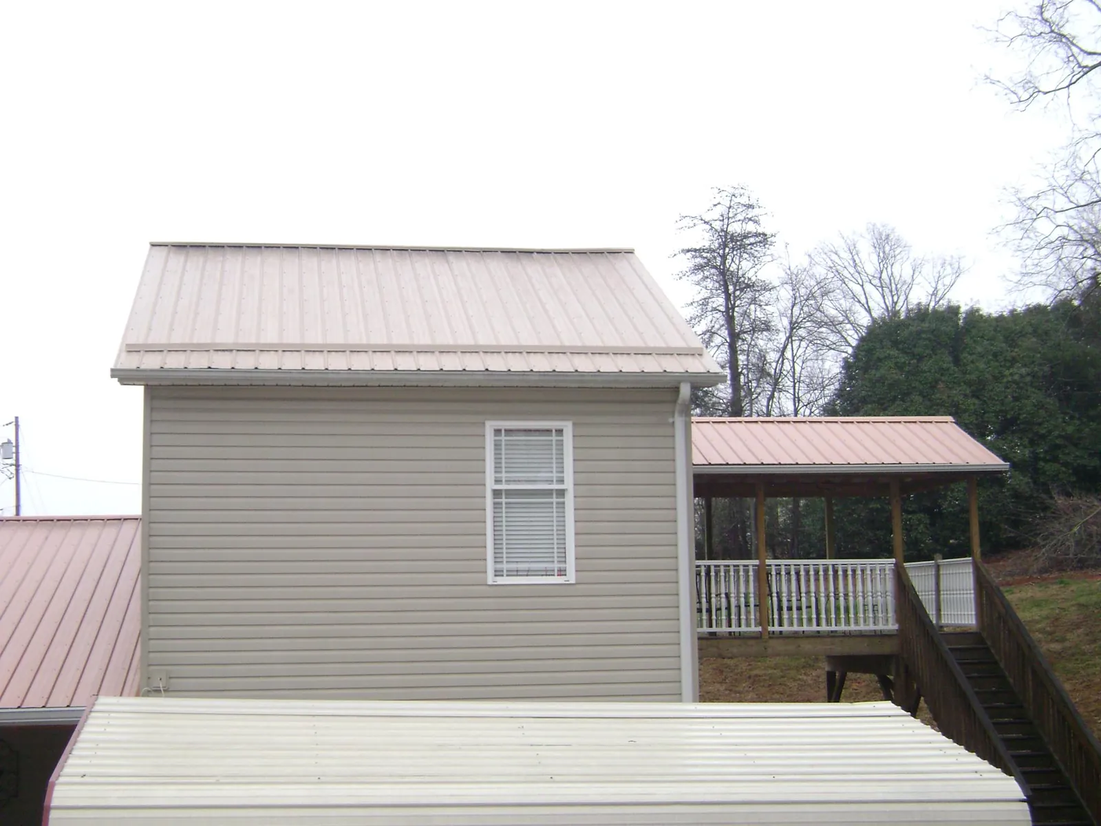 Tan metal roofs on a two story addition and attached porch, from a Roof Replacement job in Antwerp