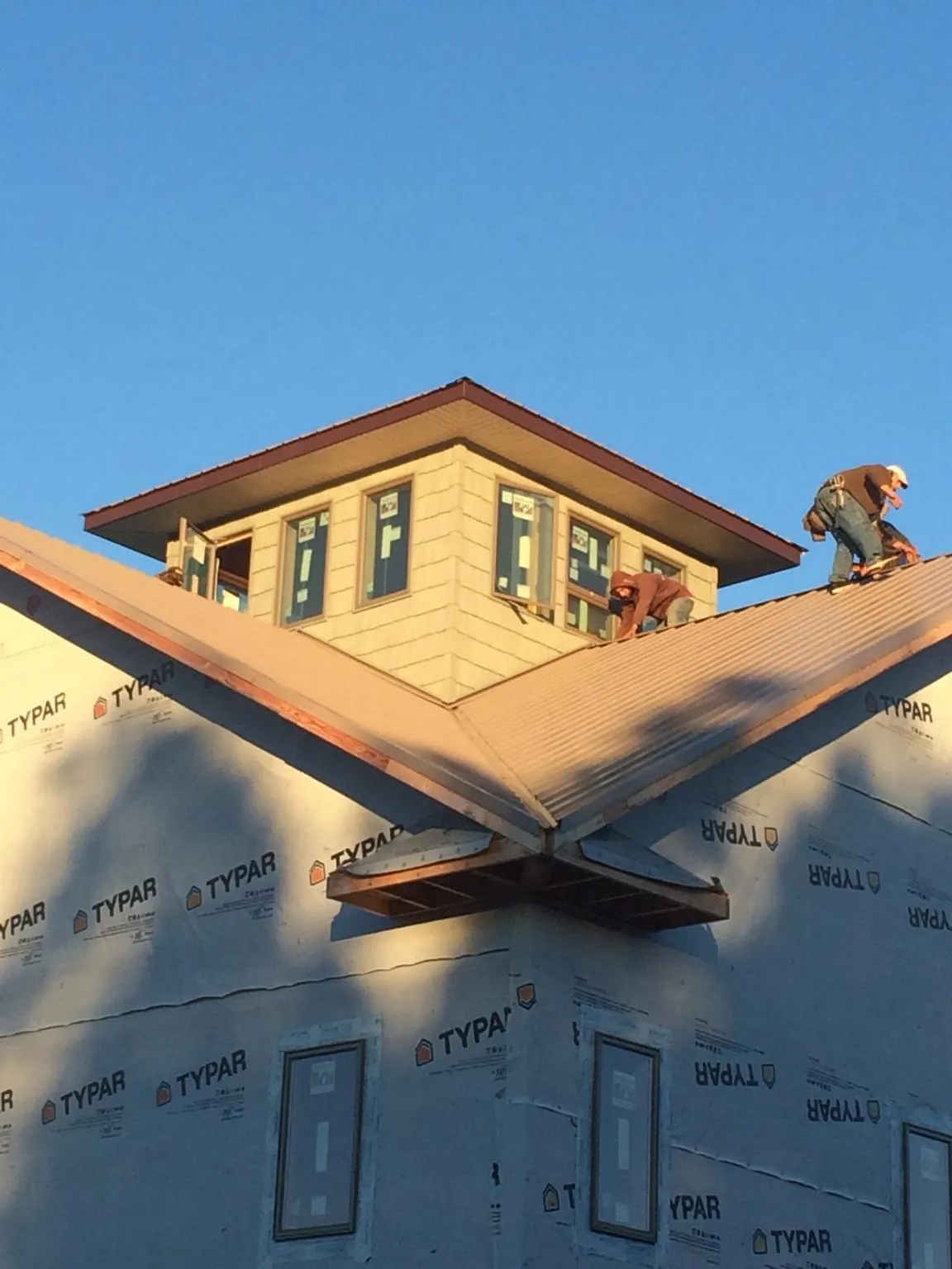 Roofers working around a rooftop cupola on a new metal roof at sunset — Roof Waterproofing in Antwerp by Roofing Brothers
